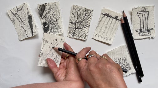 Two hands holding a pencil surrounded by small sketches